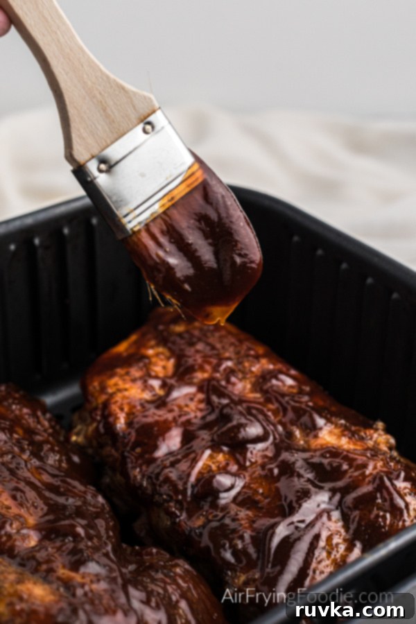 Ultimate Air Fryer BBQ Ribs 8 Air Fryer Ribs being slathered generously with BBQ sauce before serving to enhance flavor and appearance.