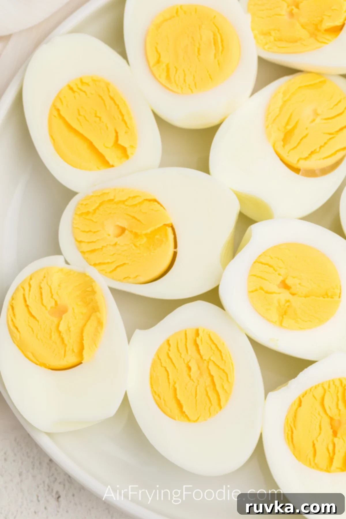 Boil-Free Hard Boiled Eggs in Your Air Fryer 6 Air Fried Eggs on a white plate and cut in half, ready to serve.