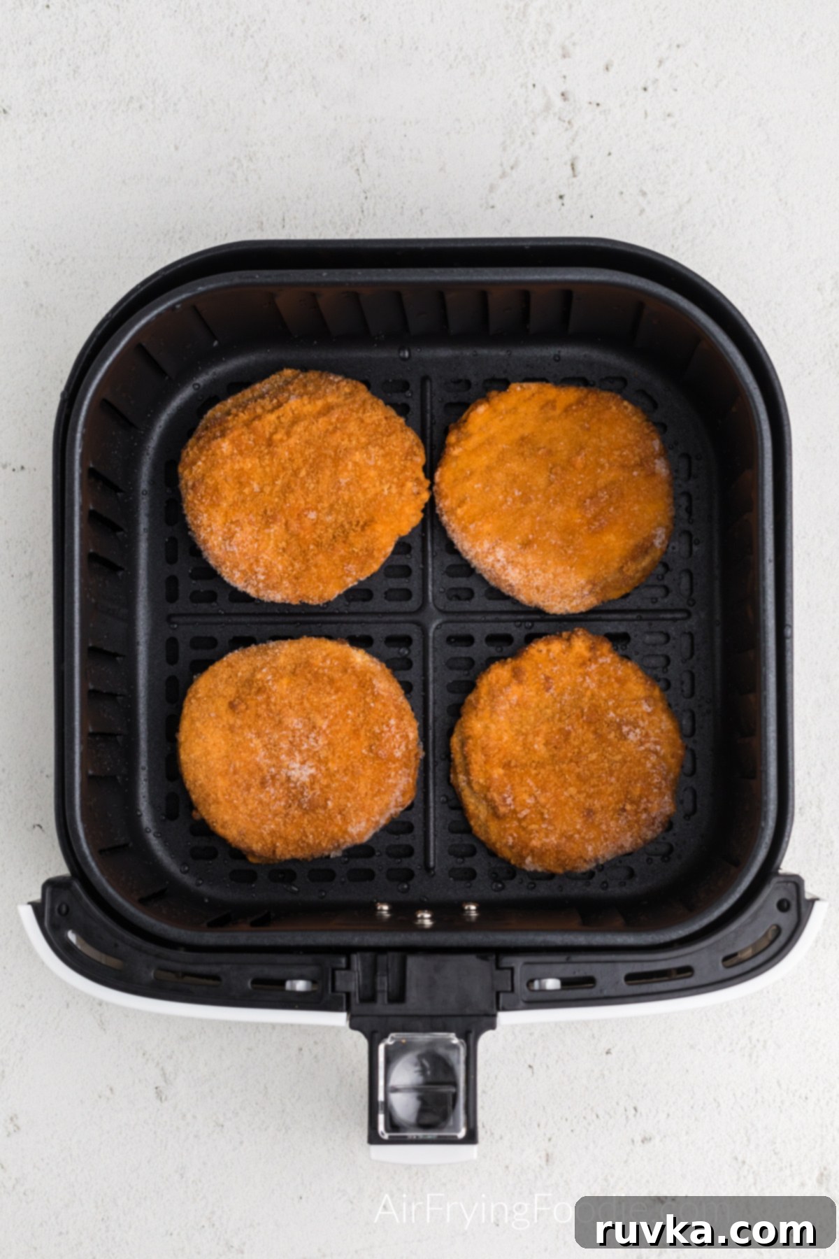 Quick and Crispy Air Fryer Frozen Chicken Patties 5 Frozen chicken patties arranged in a single layer in an air fryer basket, ready for cooking.