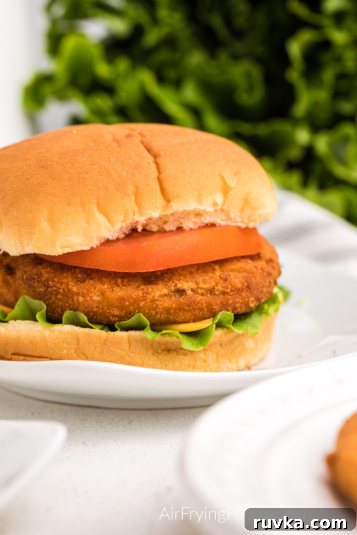 Quick and Crispy Air Fryer Frozen Chicken Patties 7 A fully cooked, golden-brown chicken patty on a brioche bun with a slice of cheese, fresh lettuce, and tomato, highlighting the crispy breading and appealing presentation.
