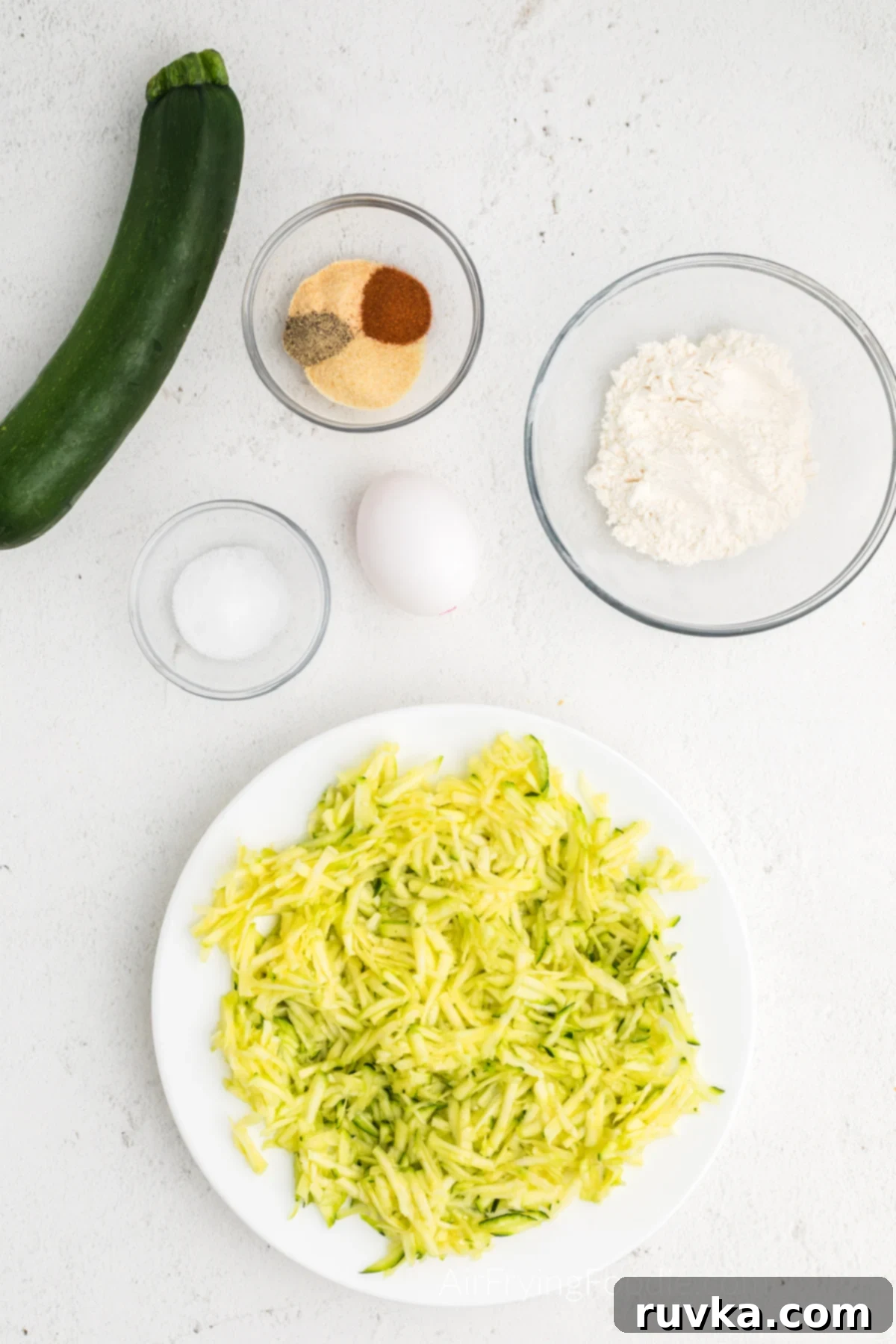 Crispy Air Fryer Zucchini Fritters 4 Shredded Zucchini resting on a white plate, ready for the next step.
