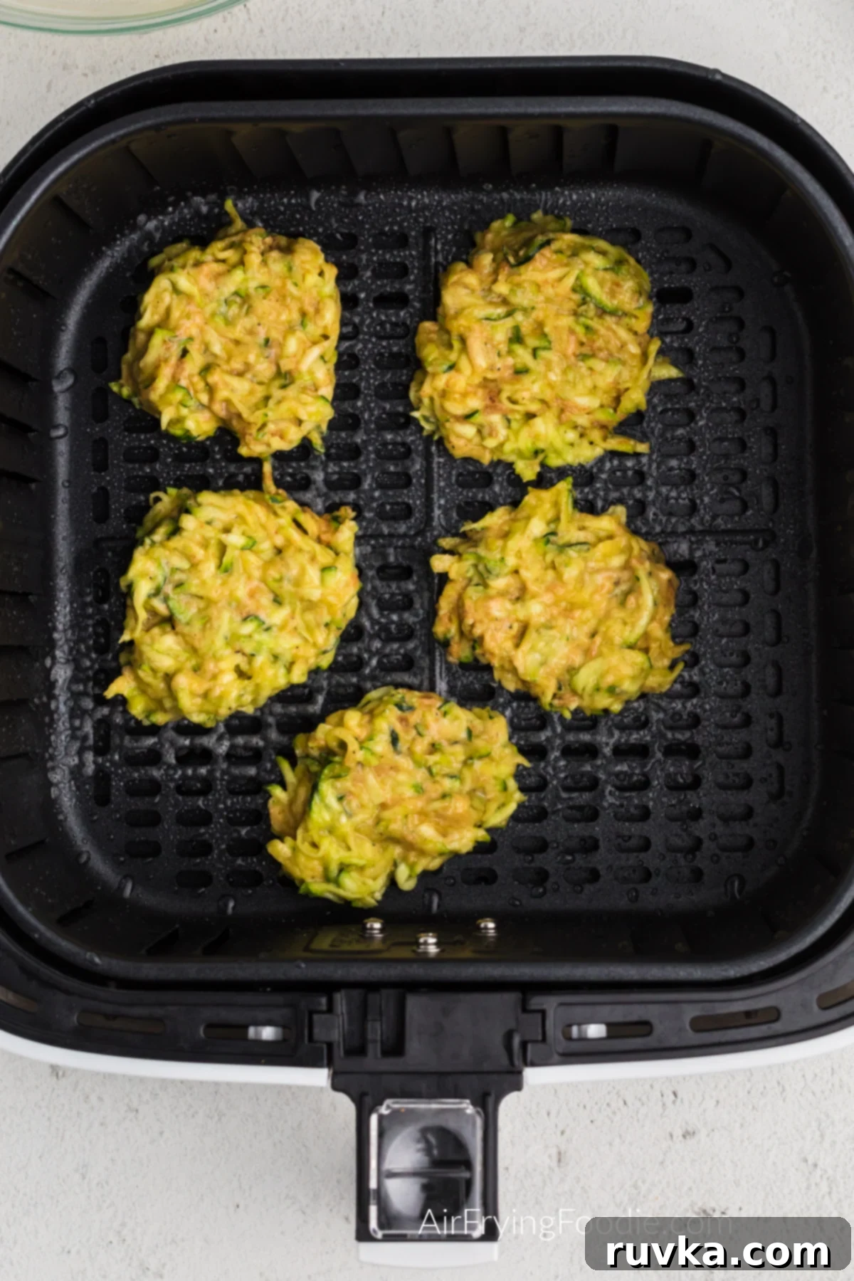 Crispy Air Fryer Zucchini Fritters 6 Zucchini fritter batter carefully scooped onto the basket of the air fryer, ready to cook.