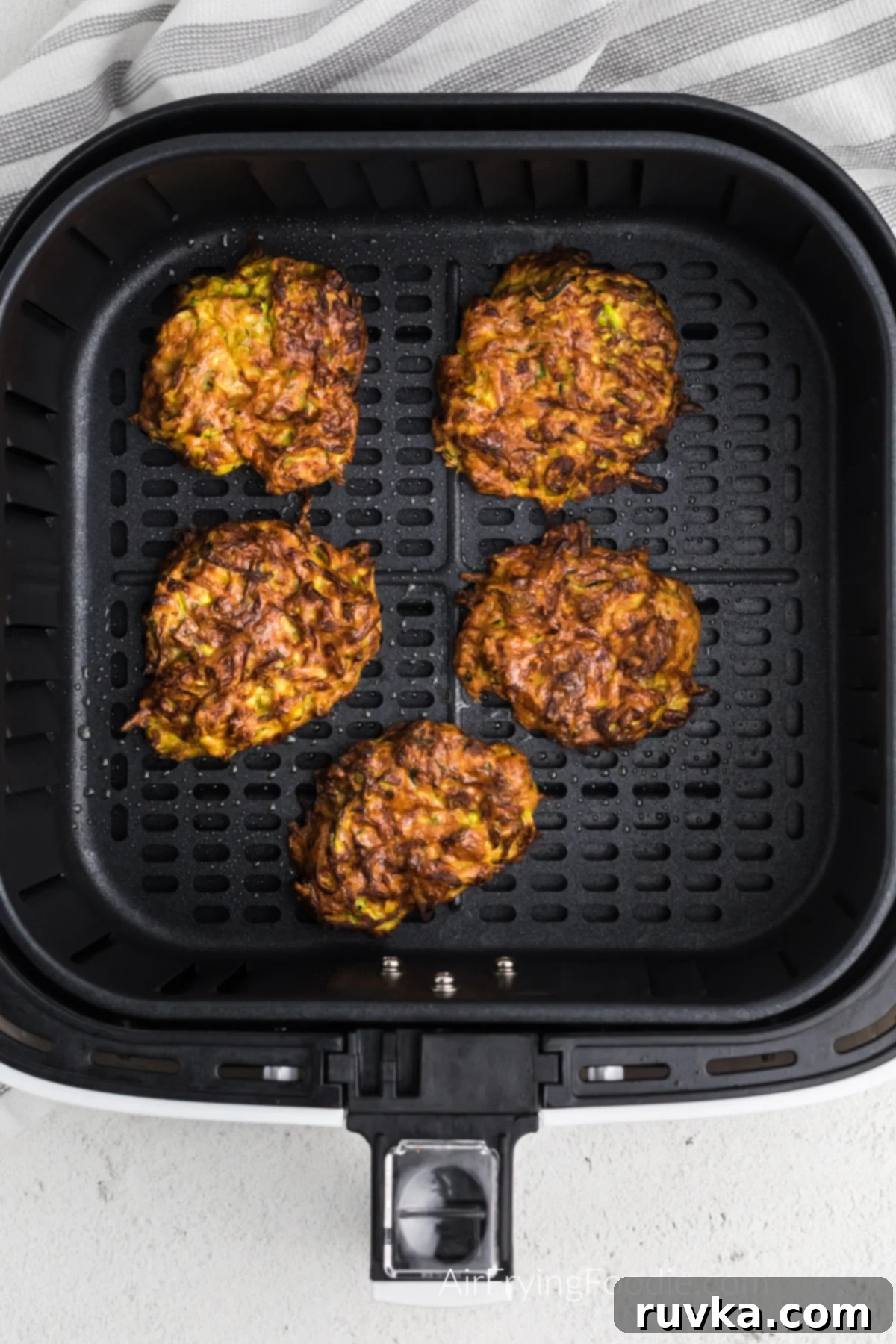 Crispy Air Fryer Zucchini Fritters 7 Freshly fried zucchini fritters, golden and crispy, in the basket of the air fryer.
