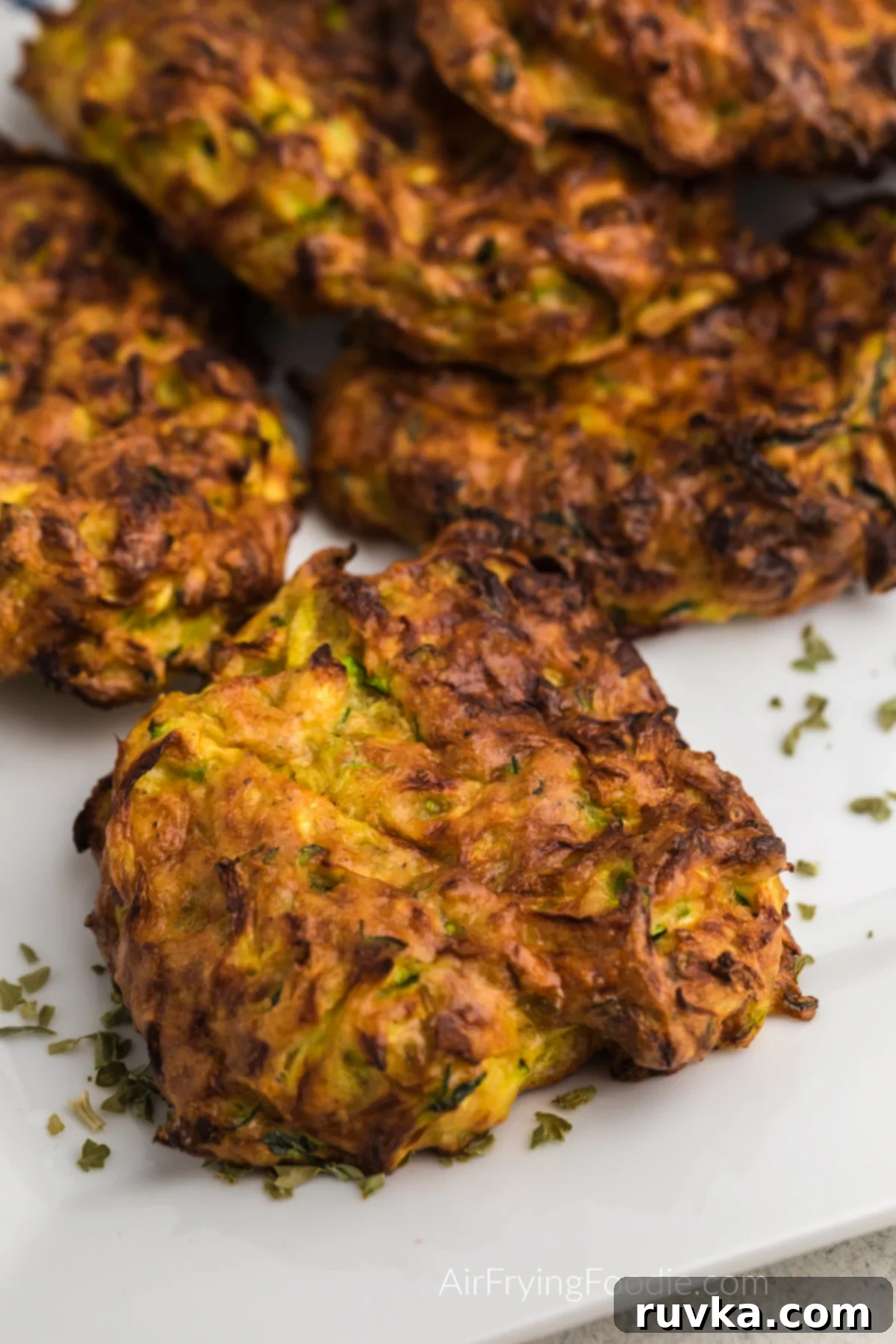 Crispy Air Fryer Zucchini Fritters 9 Perfectly crispy Zucchini fritters arranged beautifully on a white plate, ready to serve.