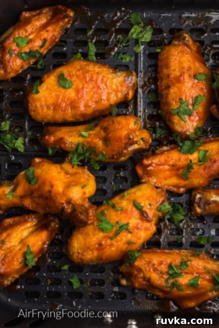 Crispy Air Fryer Chicken Wings 2 Crispy Air Fryer chicken wings in the basket of the air fryer and garnished with fresh parsley.