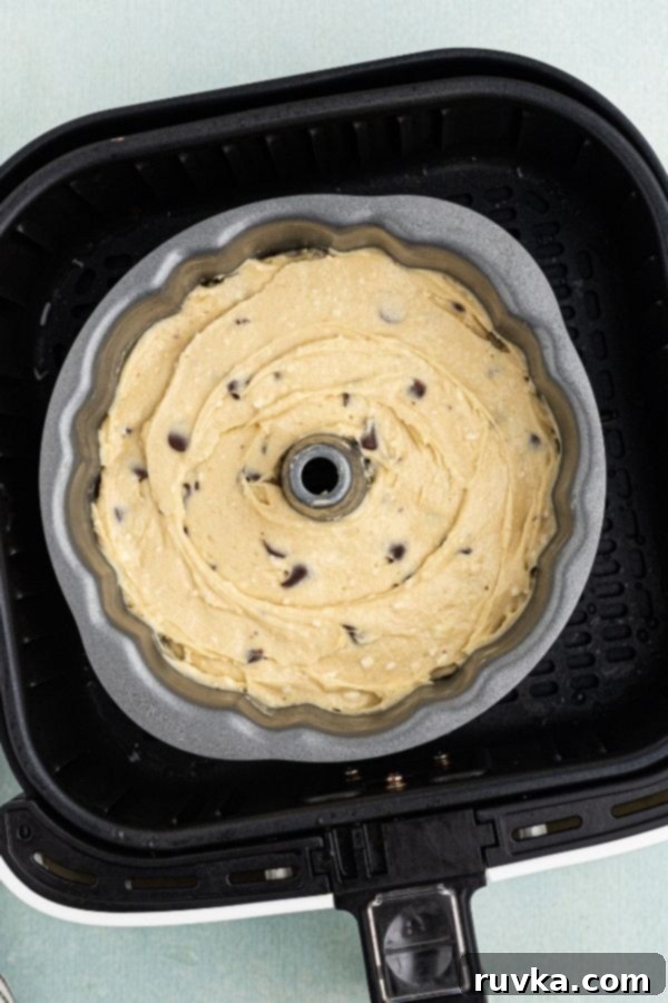 Air Fried Chocolate Chip Pound Cake 3 Uncooked raw pound cake batter in a bundt cake pan set in an air fryer basket, ready for baking.