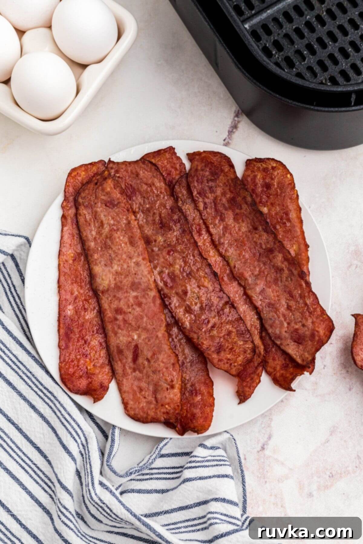 Crispy Air Fryer Turkey Bacon 6 Crispy, golden-brown turkey bacon expertly stacked on a white plate, ready to be part of a delightful meal.