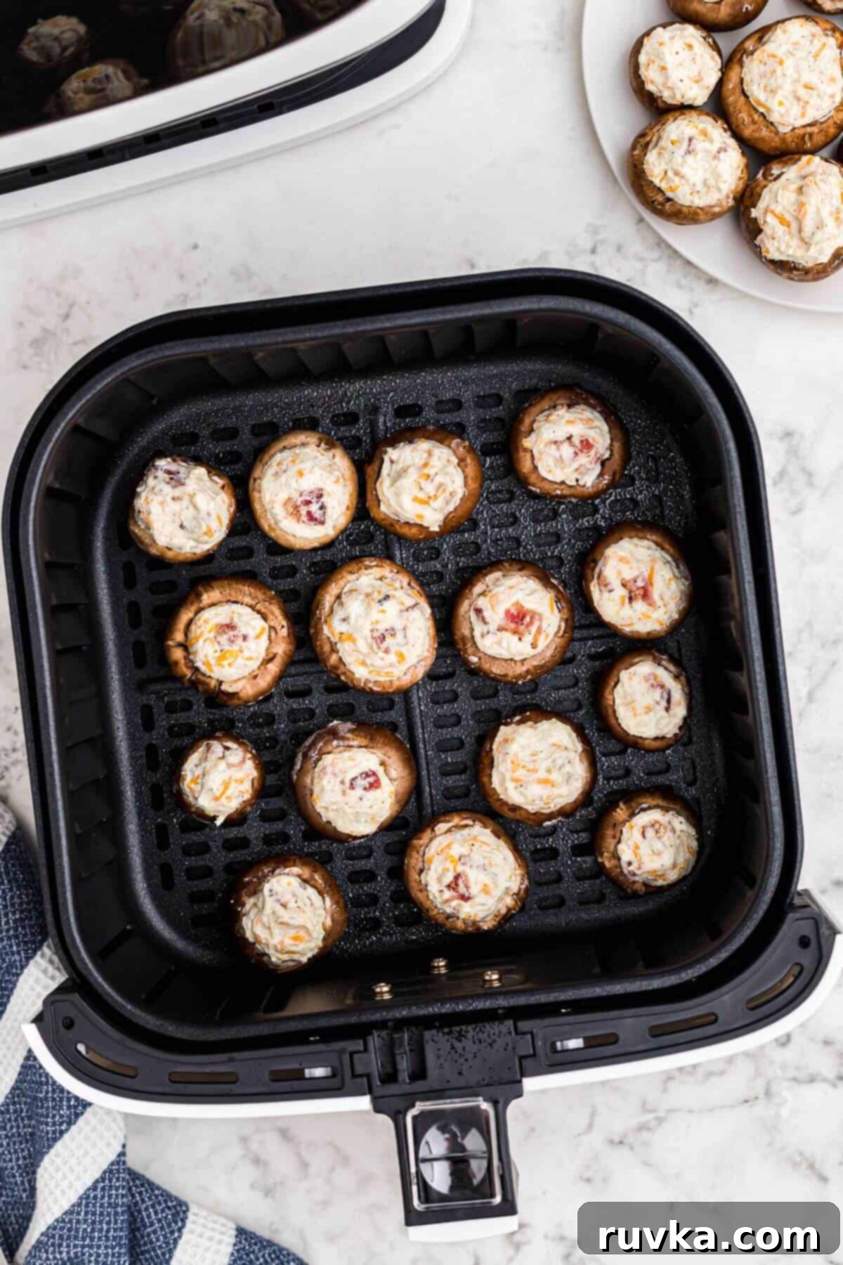 Ultimate Air Fryer Stuffed Mushrooms 5 Mushroom caps stuffed with a cream cheese mixture in the air fryer basket before air frying.