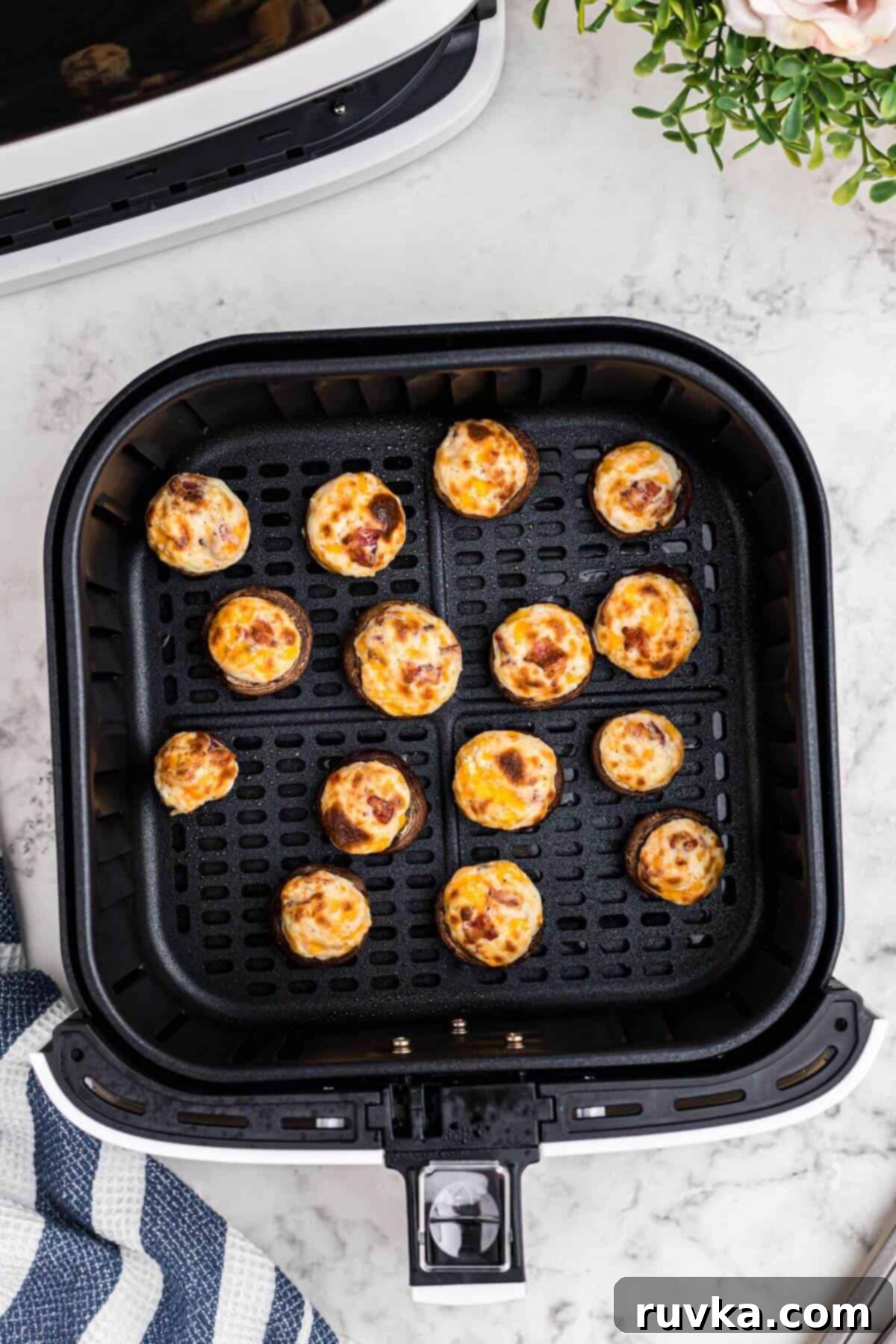 Ultimate Air Fryer Stuffed Mushrooms 6 Golden brown mushrooms stuffed with cream cheese, cheddar cheese, bacon crumbles, in the air fryer basket after being cooked.