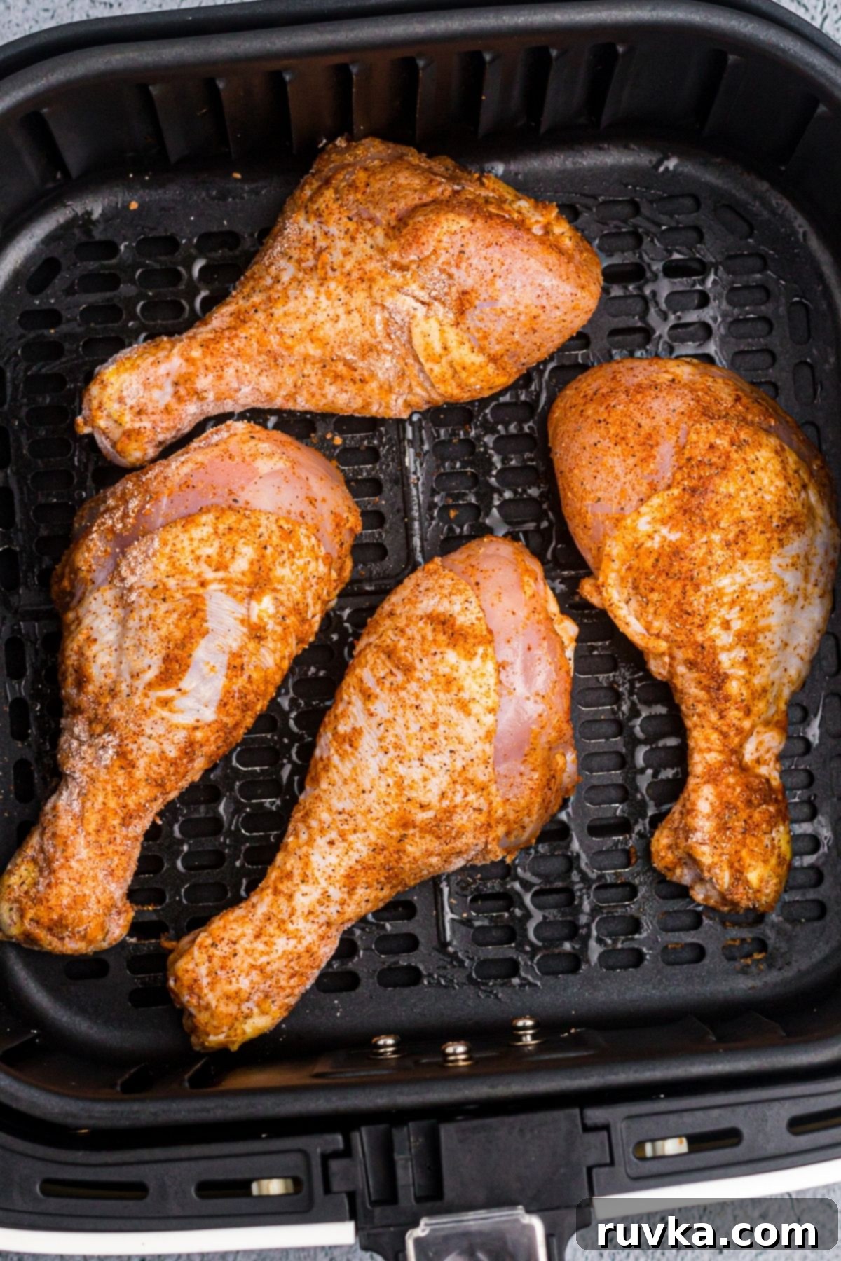 Crispy Air Fryer Drumsticks 6 Seasoned chicken drumsticks in the air fryer basket before being cooked.