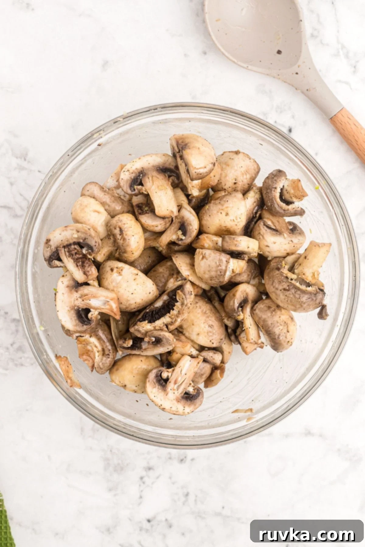 Perfectly Crispy Air Fryer Mushrooms 5 Glass bowl filled with mushrooms tossed with butter and seasonings