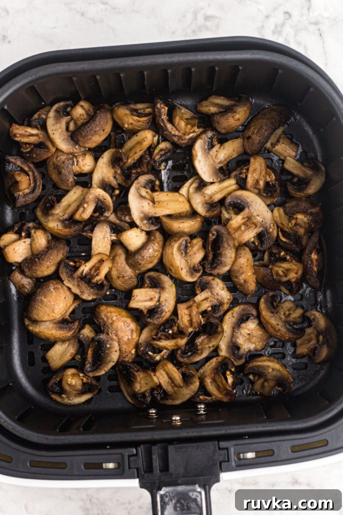 Perfectly Crispy Air Fryer Mushrooms 7 Juicy cooked mushrooms in the air fryer basket.