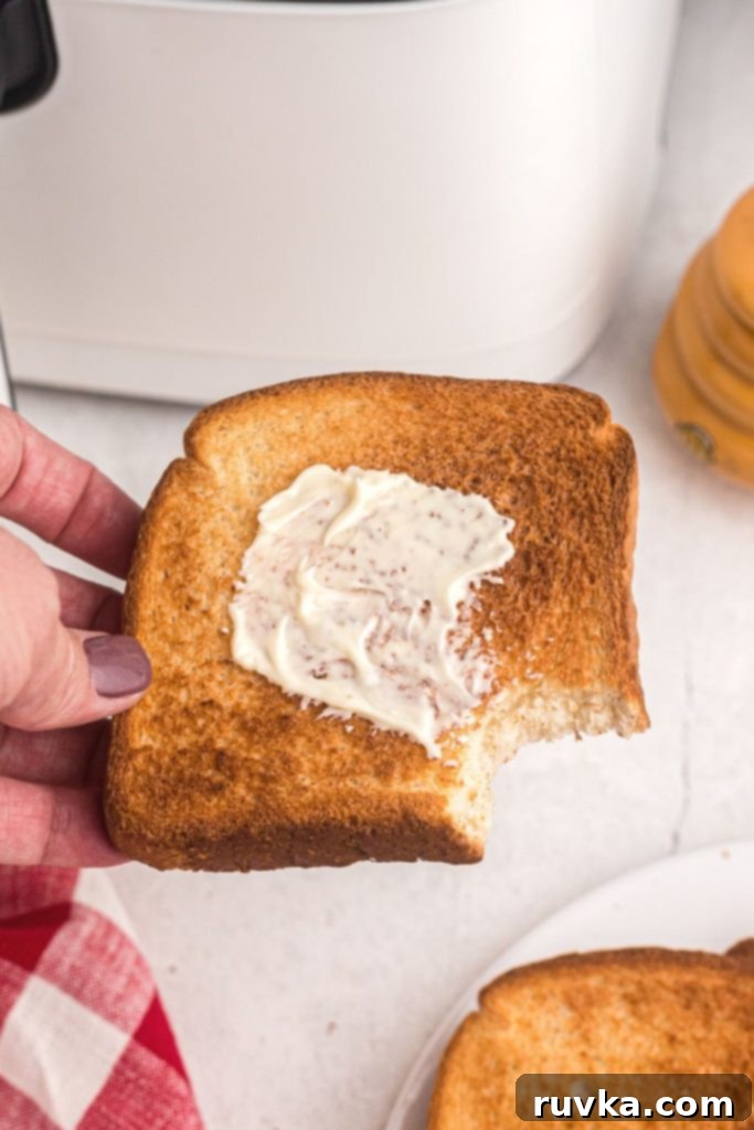 The Ultimate Air Fryer Toast 6 Golden slice of air fryer toast being held with a bite missing