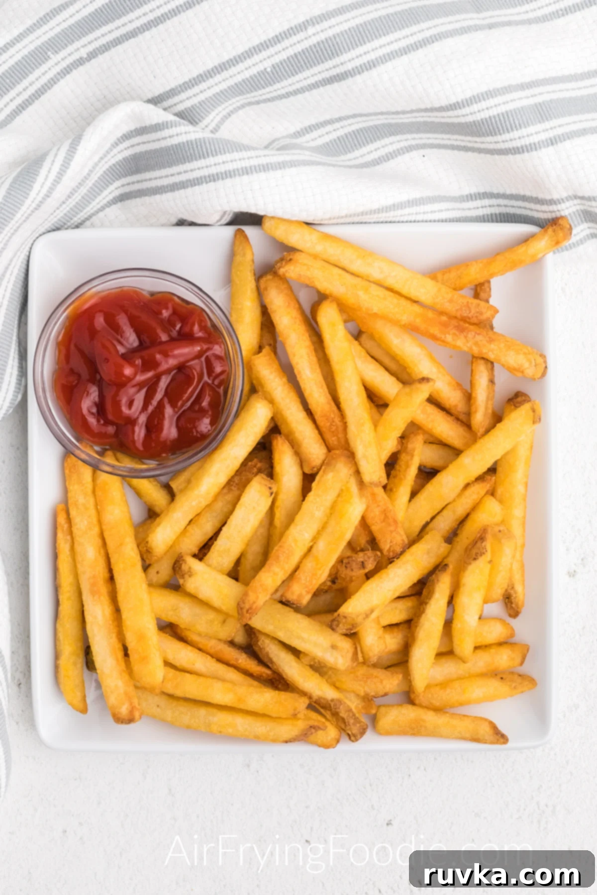 Crispy Air Fryer Frozen French Fries 2 Crispy golden French fries made in the air fryer from frozen, served on a white plate with a side of ketchup.