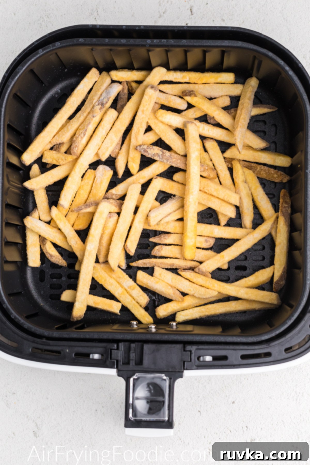 Crispy Air Fryer Frozen French Fries 4 Frozen French fries neatly arranged in the basket of an air fryer before cooking.