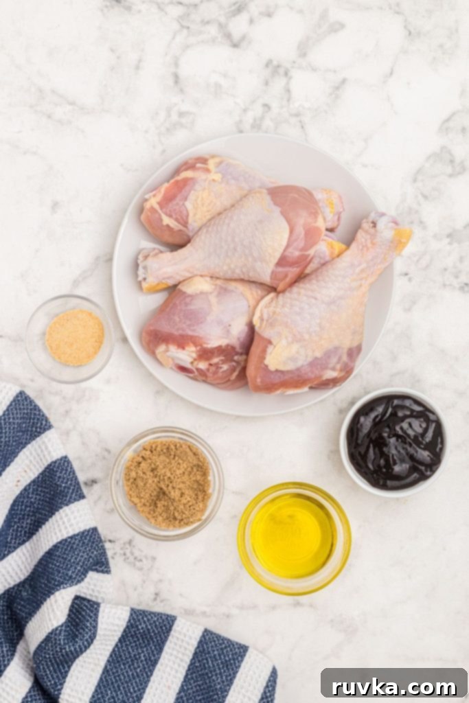 Crispy Air Fryer BBQ Chicken 4 Uncooked chicken drumsticks on a white plate with sauce and spices measured in small glass bowls.