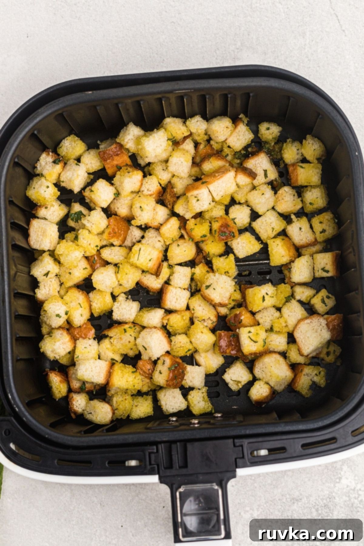 Perfectly Crispy Air Fryer Croutons 5 Uncooked seasoned cubes of bread in the air fryer basket.