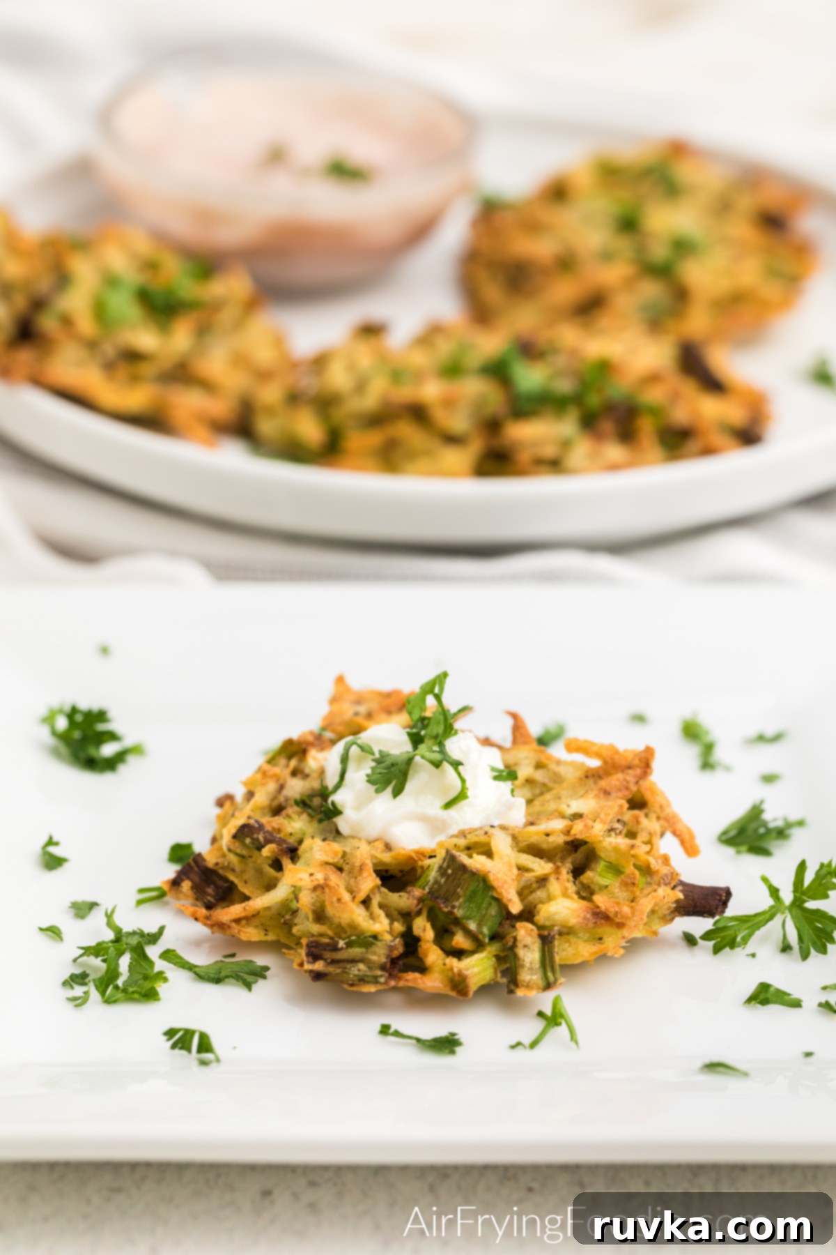 Crispy Air Fryer Latkes 2 Air Fried Latke on a plate and topped with fresh parsley and sour cream.