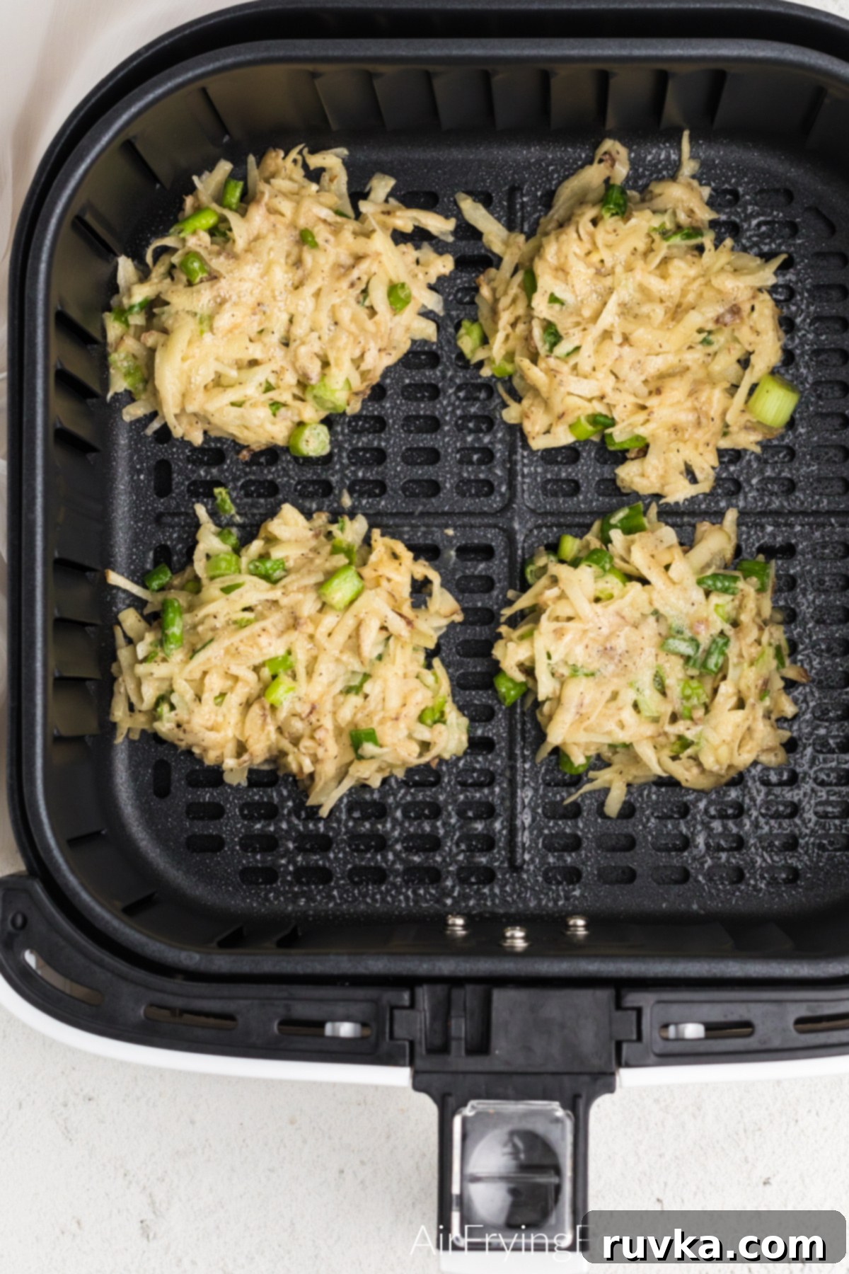 Crispy Air Fryer Latkes 7 Latkes in the basket of the air fryer ready to be cookes.