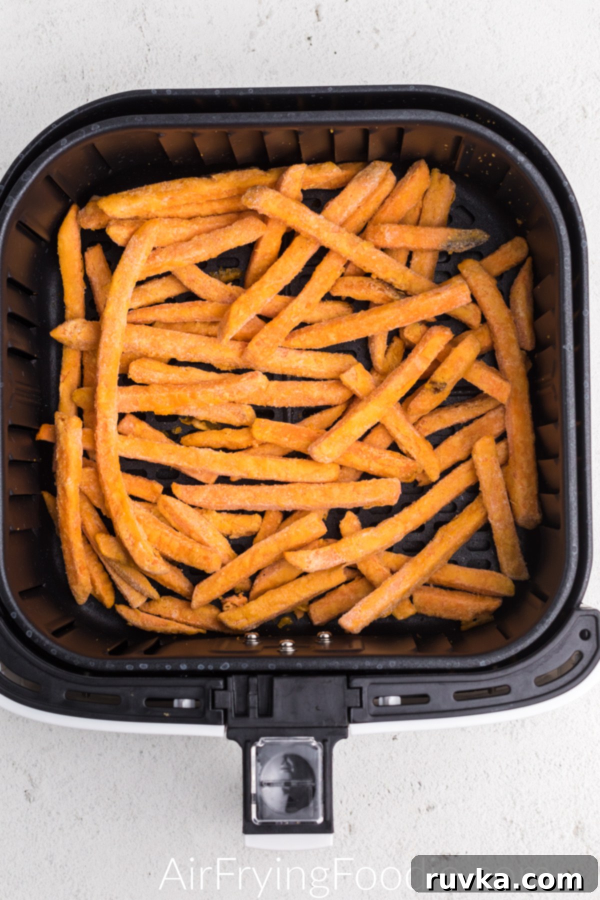 Frozen Sweet potato fries in the basket of the air fryer.