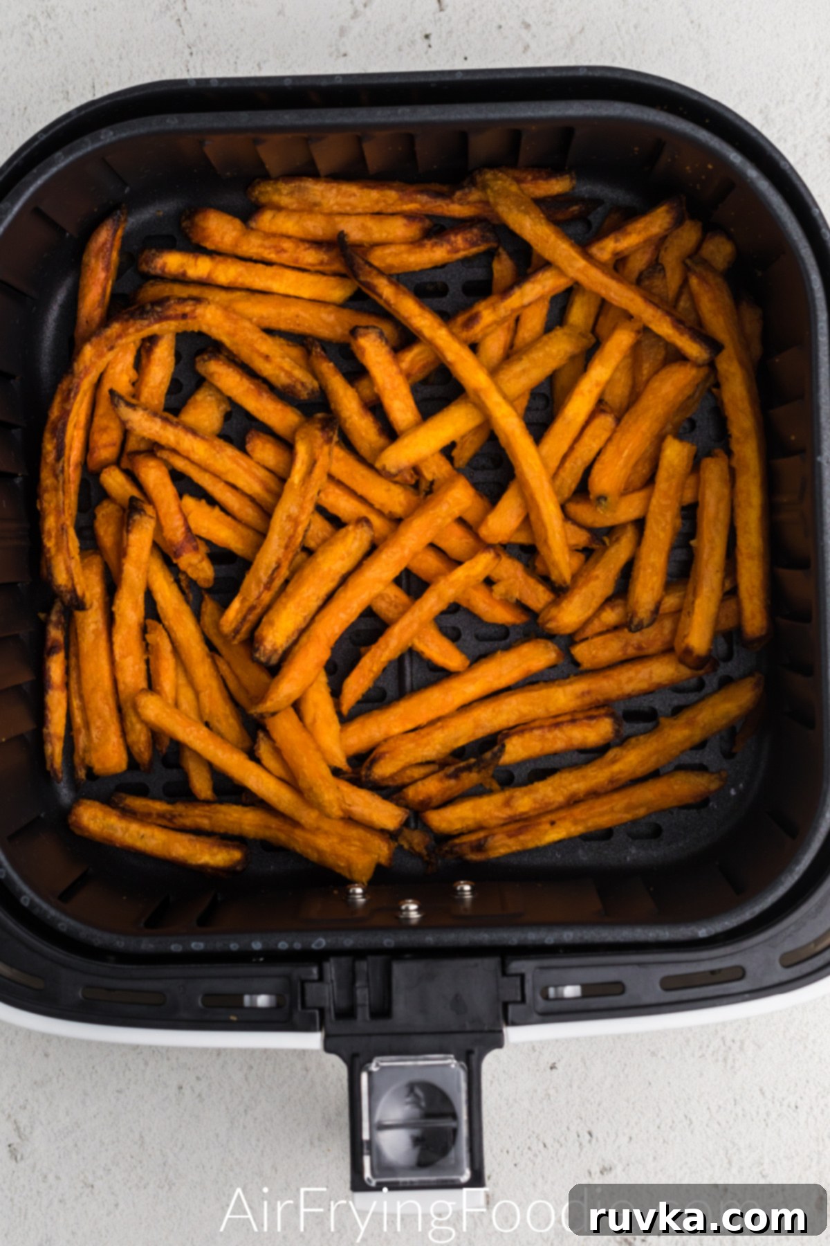 Sweet potato fried cooked in the basket of the air fryer and ready to serve.