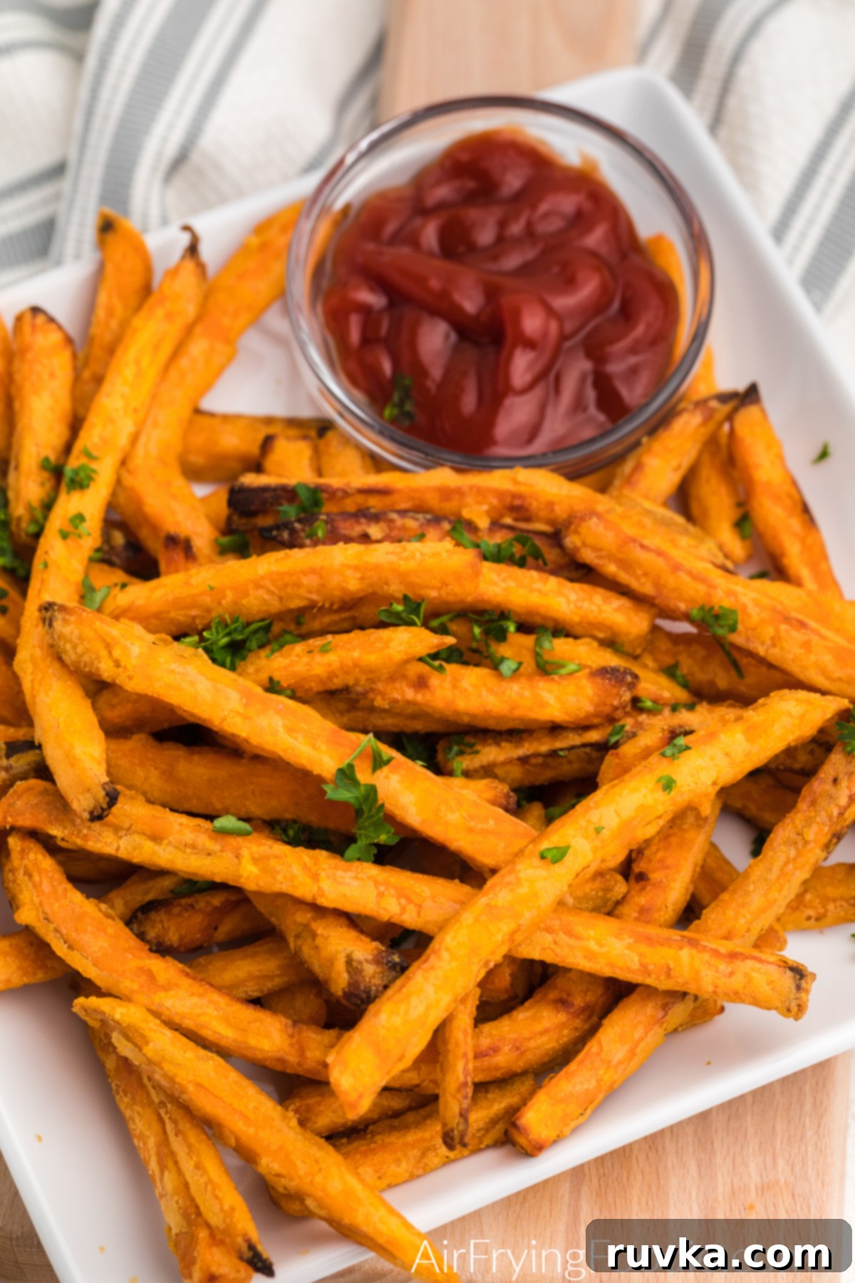 Plate full of cooked sweet potato fries with a side of ketchup.