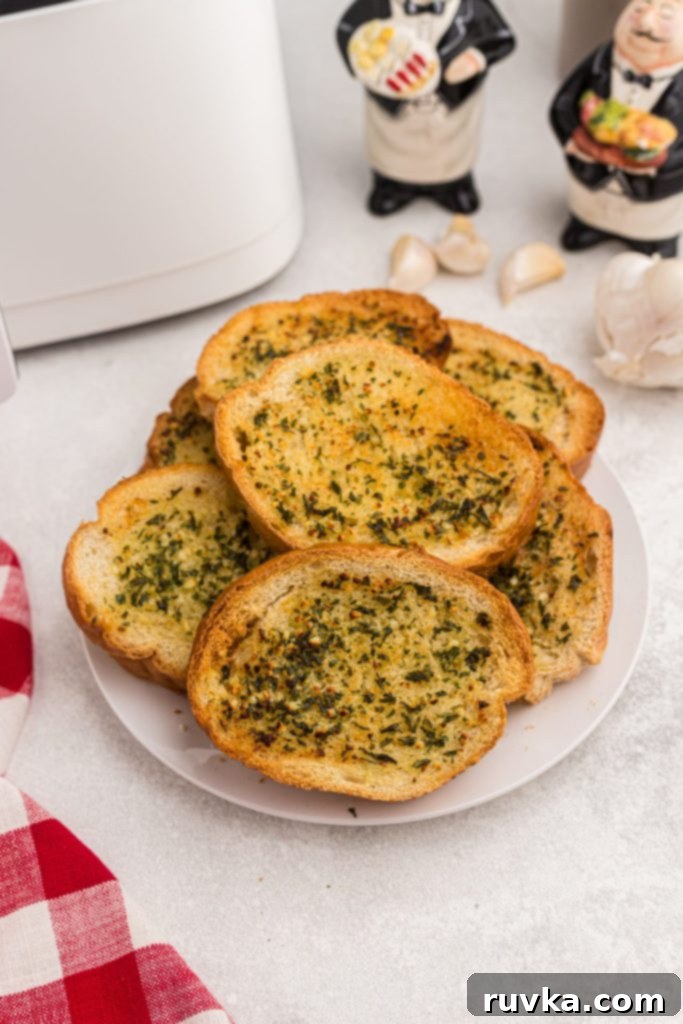 Perfect Air Fryer Garlic Bread 2 A white plate filled with golden, perfectly toasted garlic bread slices, accompanied by a vibrant red linen on the table, showcasing its delicious appeal.
