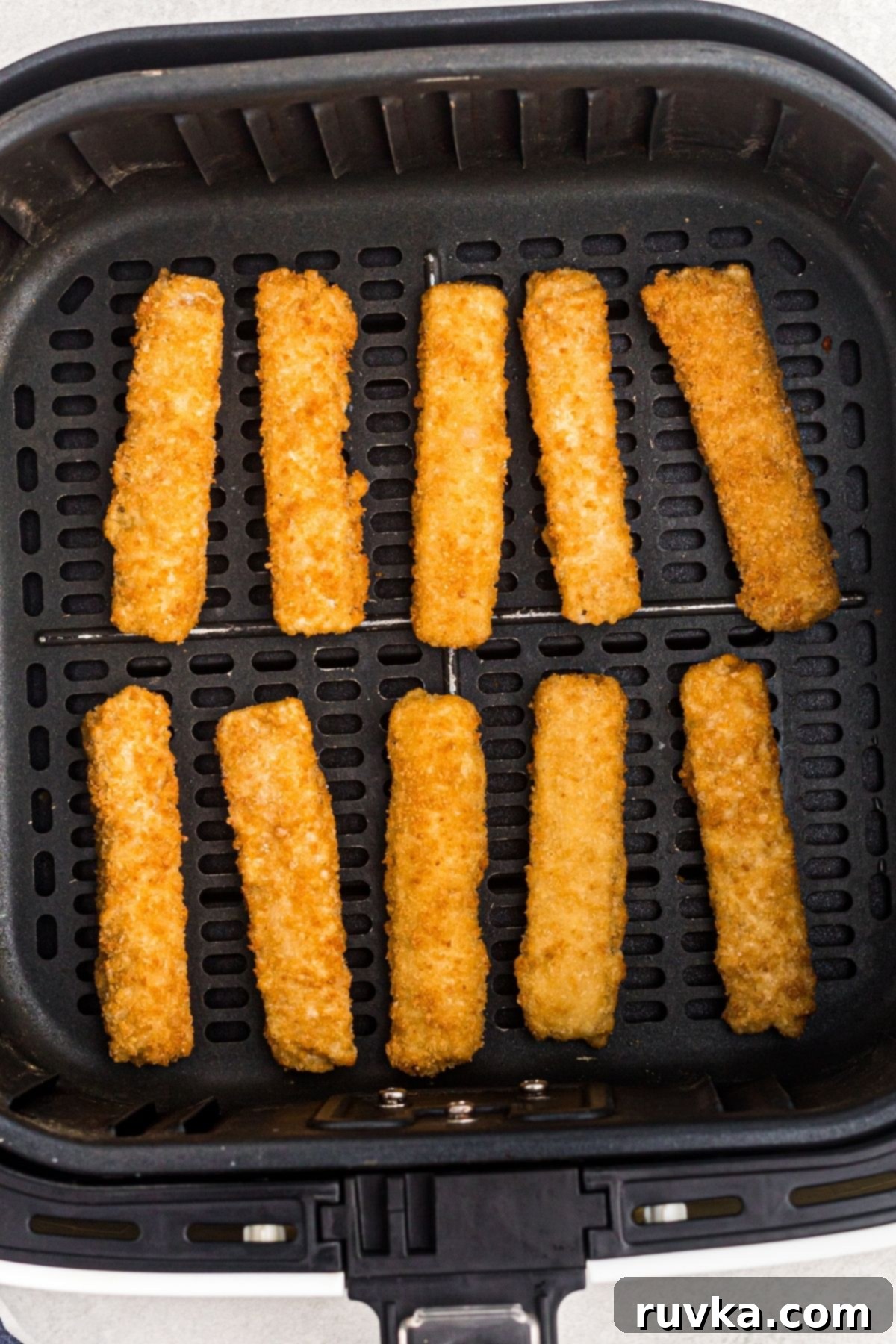 Crispy Air Fryer Fish Sticks 4 Golden fish sticks before being fried in an air fryer basket