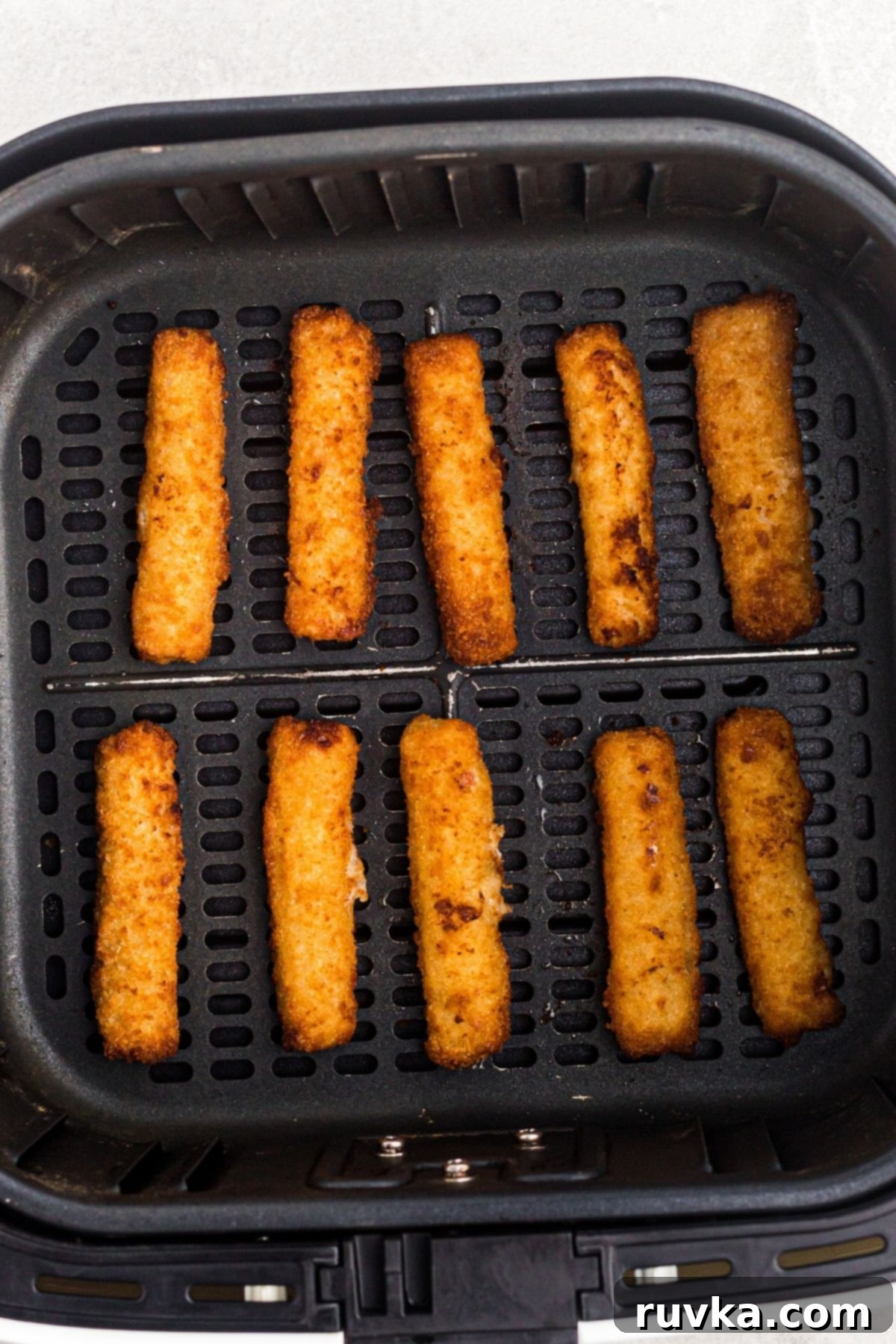 Crispy Air Fryer Fish Sticks 5 golden fried fish sticks in an air fryer basket