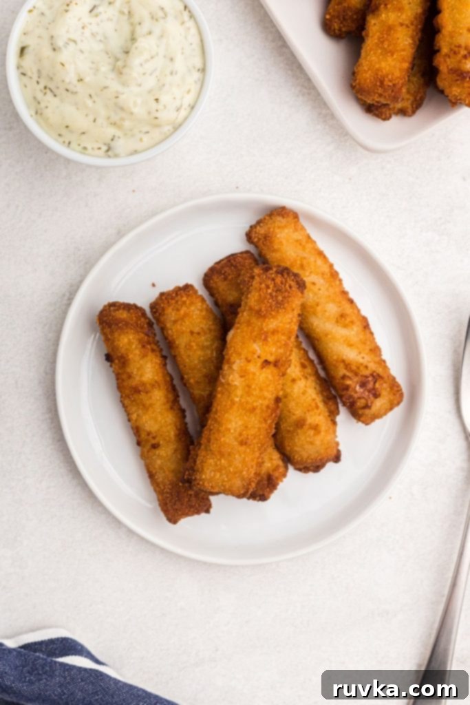 Crispy Air Fryer Fish Sticks 6 Small white plate with fish sticks served next to large dish filled with fish sticks