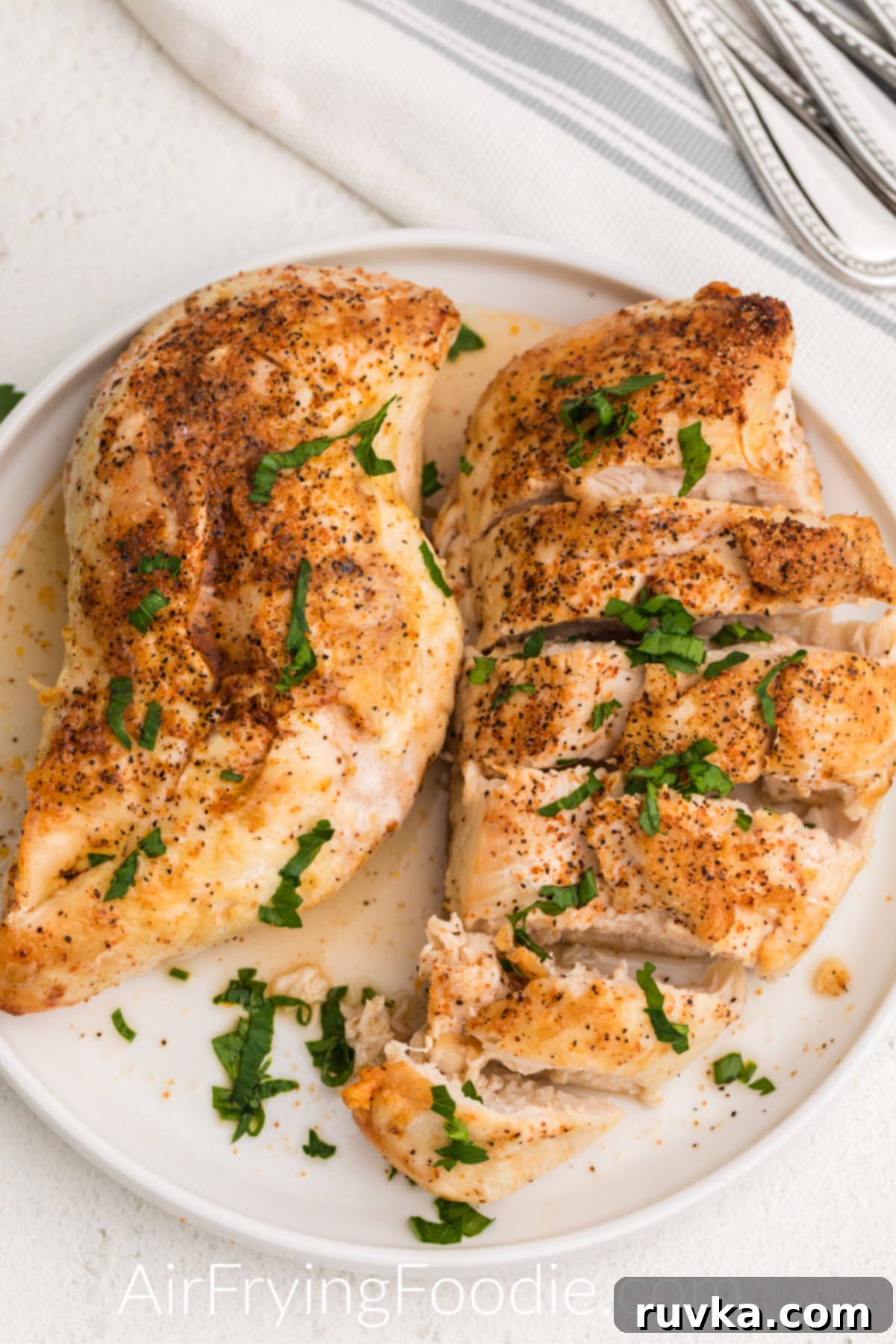 Perfect Air Fryer Frozen Chicken Breast 2 Fully cooked chicken that was cooked from frozen in the air fryer, seasoned and served on a white plate.