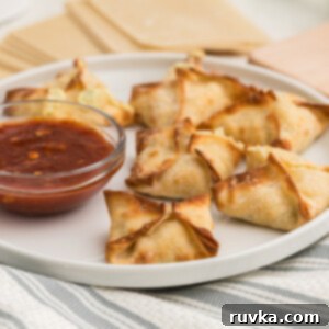 Crispy Air Fryer Crab Rangoon 9 Air Fryer Crab Rangoon on a white plate with dipping sauce on the side.