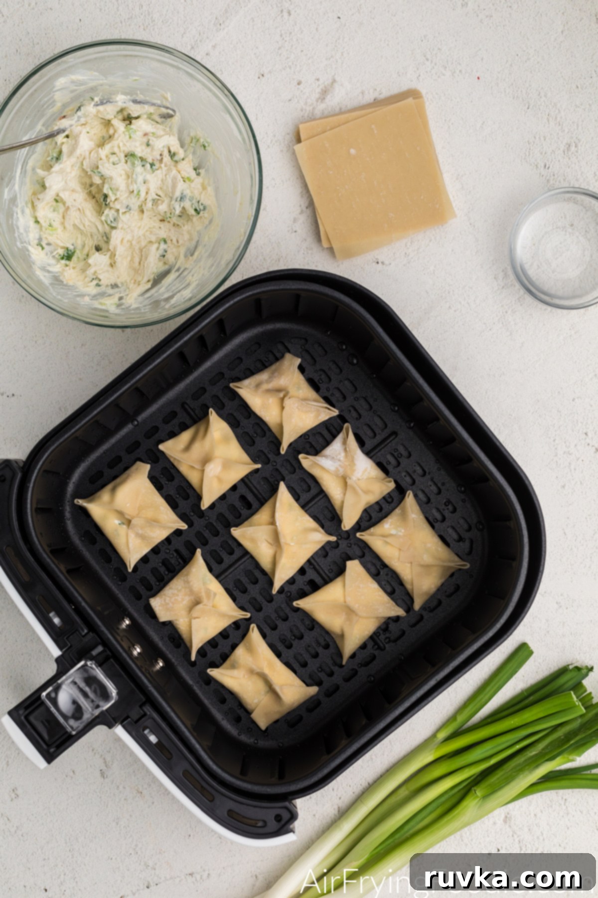 Crispy Air Fryer Crab Rangoon 6 Wonton wrappers with cream cheese mixture ready to cook in the air fryer basket.