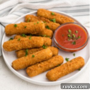 Frozen Food Favorites for the Air Fryer 11 Crispy Air Fryer Mozzarella Sticks on a white plate with marinara dipping sauce and topped with fresh parsley.