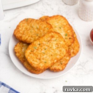 Frozen Food Favorites for the Air Fryer 13 Golden, crispy hash brown patties on a white plate, served with a side of ketchup, fresh from the air fryer.