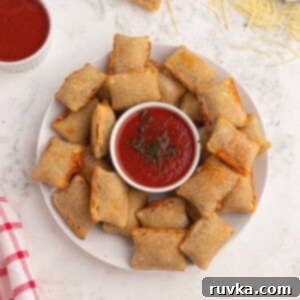 Frozen Food Favorites for the Air Fryer 17 Crispy cooked pizza rolls served on a white plate, sprinkled with shredded parmesan cheese and a side of red dipping sauce.