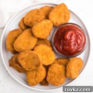 Frozen Food Favorites for the Air Fryer 3 overhead photo of perfectly crispy golden chicken nuggets made in the air fryer, served on a white plate with a side of ketchup.