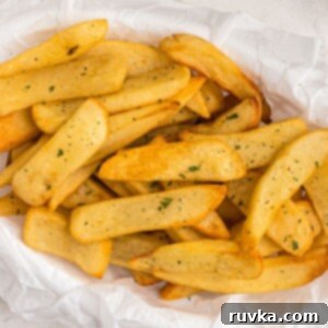 Frozen Food Favorites for the Air Fryer 4 Close up photo of golden crispy steak fries cooked and in an air fryer basket, garnished with parsley flakes, ready to serve.