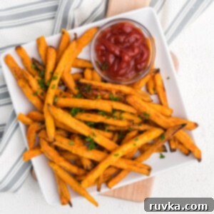 Frozen Food Favorites for the Air Fryer 6 Frozen sweet potato fries made in the air fryer - fully cooked to a golden crisp and served on a white plate with a side of ketchup.