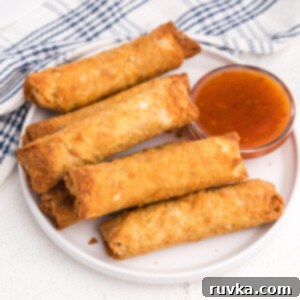 Frozen Food Favorites for the Air Fryer 8 Crispy frozen egg rolls made in the air fryer, arranged on a white plate with a side of dipping sauce.
