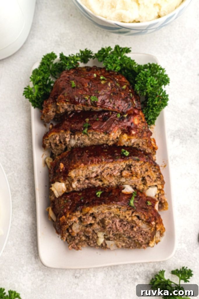 Easy Air Fryer Meatloaf 2 Golden brown meatloaf on a white square plate with parsley garnish.