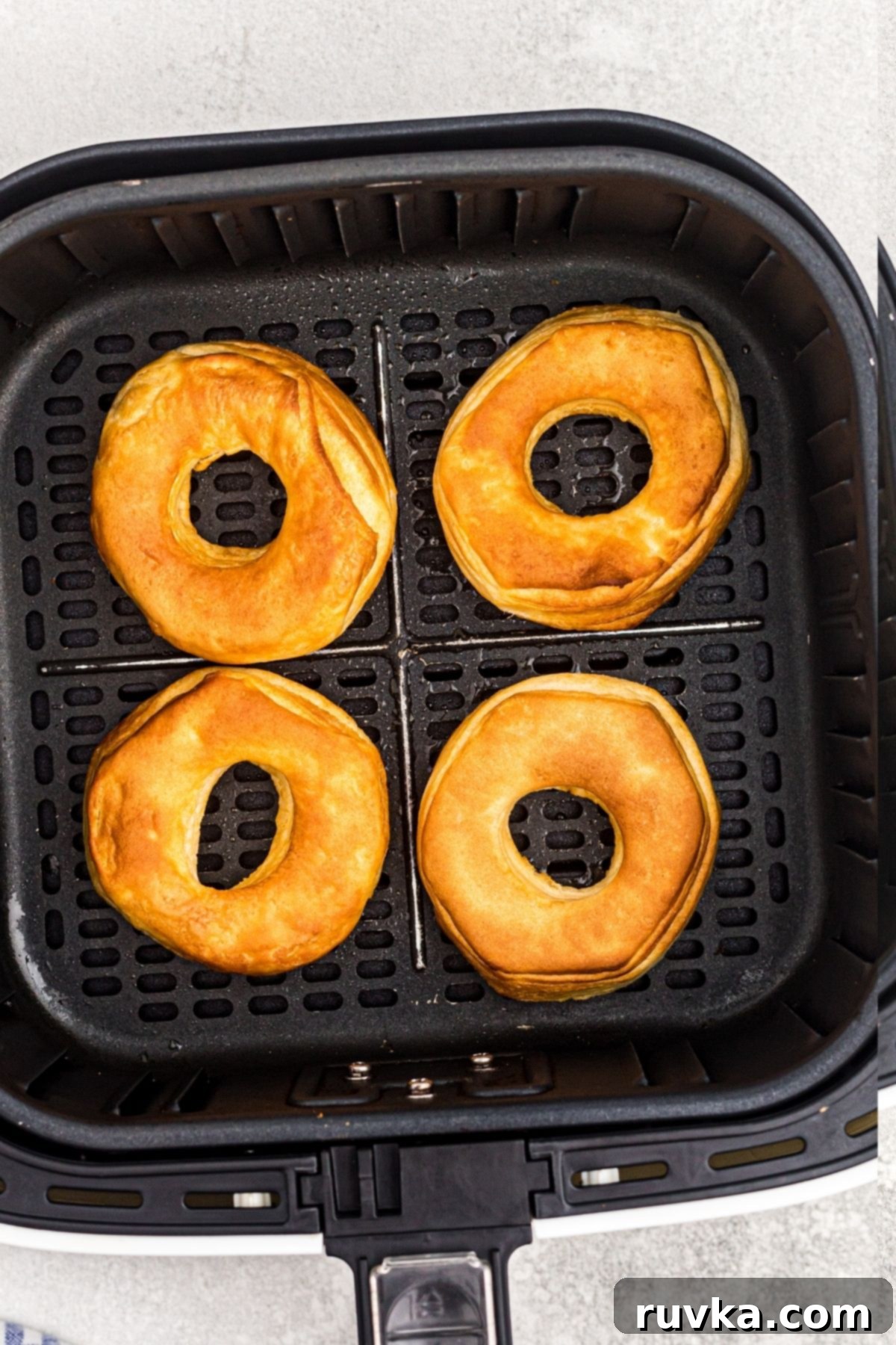 Air-Fried Donut Delights 6 Air fryer basket filled with perfectly golden brown donuts, freshly cooked and ready for toppings or glazes. The color indicates they are soft and ready to be transformed into a sweet treat.