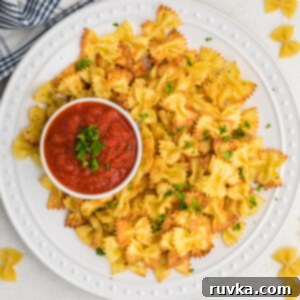 Crispy Air Fryer Pasta Chips 10 Overhead shot of air fried bow tie pasta chips with a side or marinara sauce.