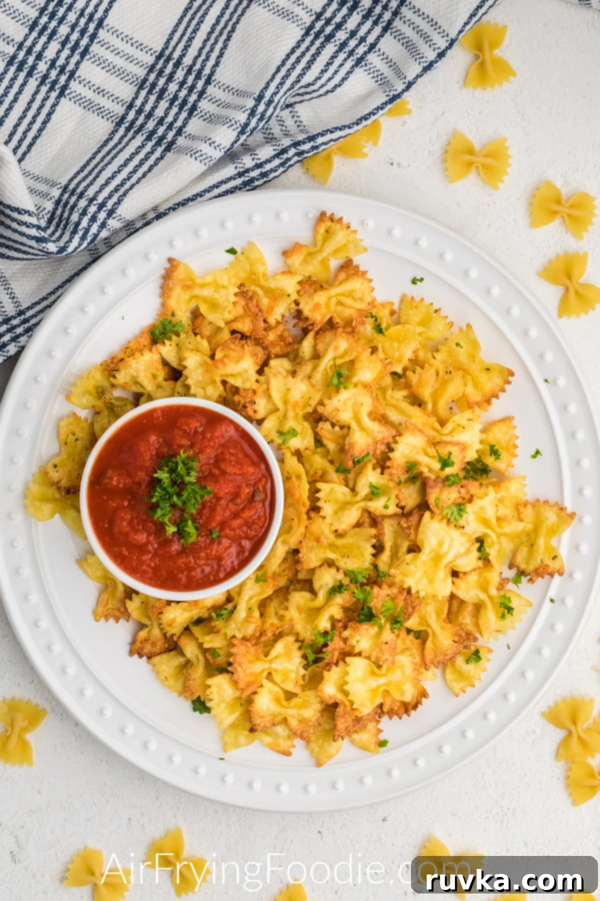Crispy Air Fryer Pasta Chips 3 Overhead shot of fried pasta chips on a white plate with a side of marinara sauce.