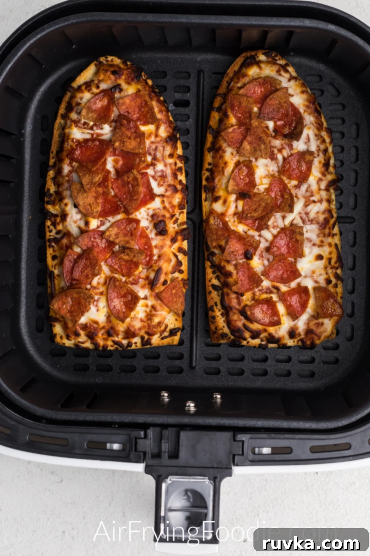 Air Fried French Bread Pizza 5 Air fried french bread pizzas in the basket of the air fryer.