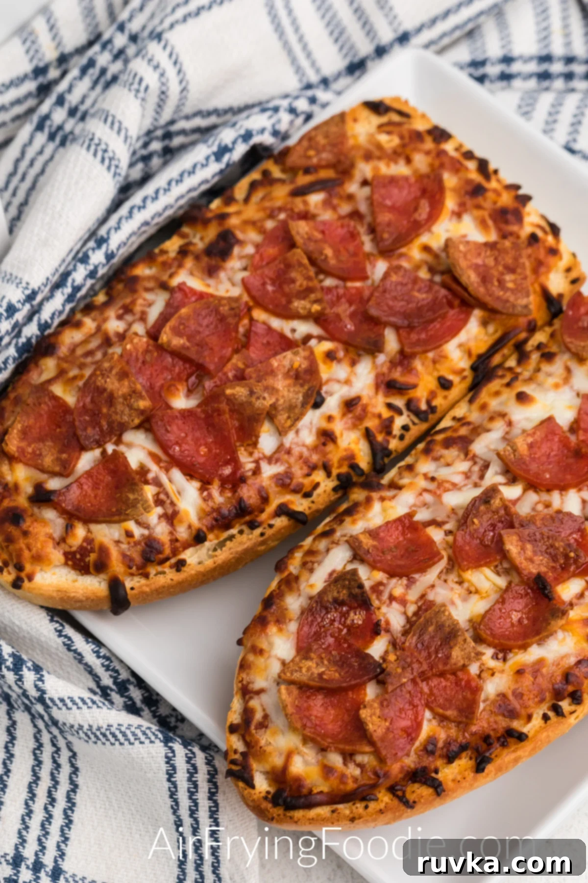 Air Fried French Bread Pizza 6 French bread pizzas cooked from frozen in the air fryer and served on a white plate.