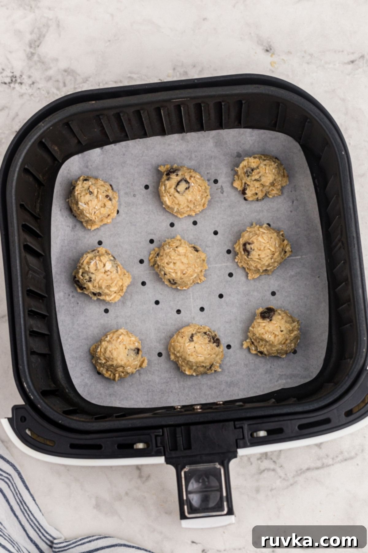 Easy Air Fryer Oatmeal Raisin Cookies 6 Balls of uncooked cookie dough in the air fryer basket.