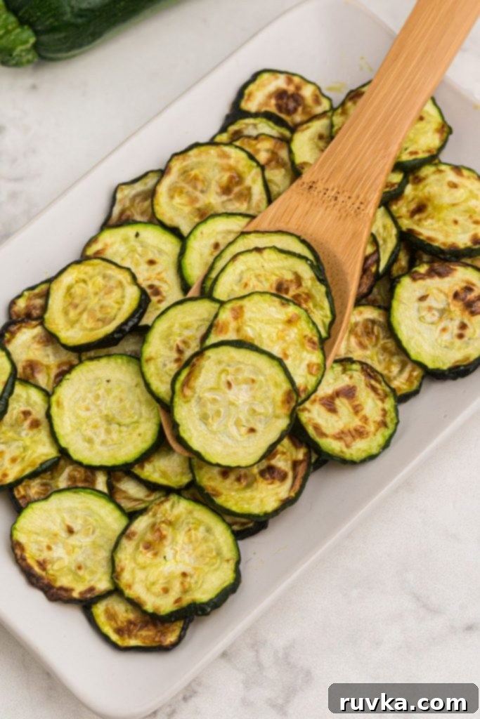 Golden Crispy Air Fryer Zucchini 2 Wooden spoon scooping golden, perfectly cooked air fryer zucchini slices from a bowl.