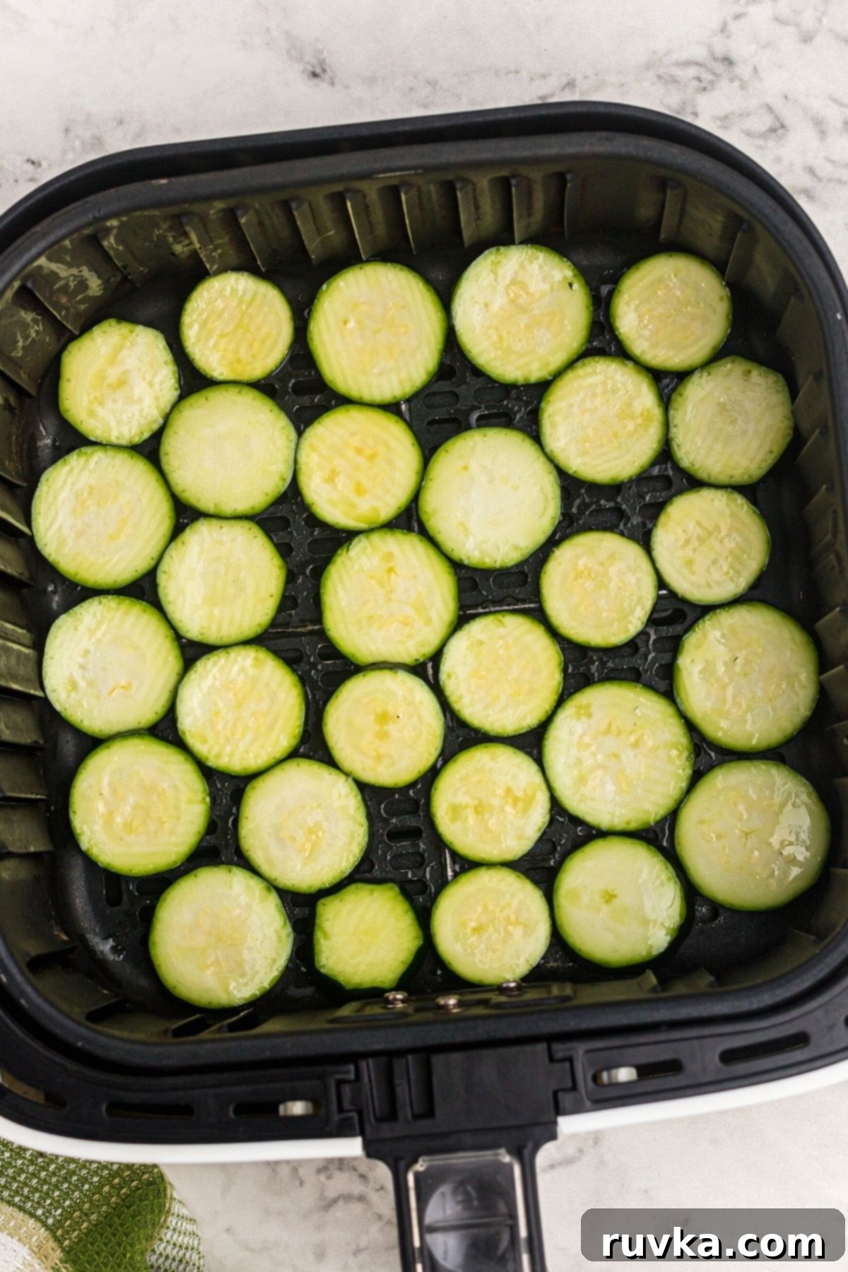 Golden Crispy Air Fryer Zucchini 5 Slices of seasoned zucchini arranged in a single layer in an air fryer basket, ready to cook.