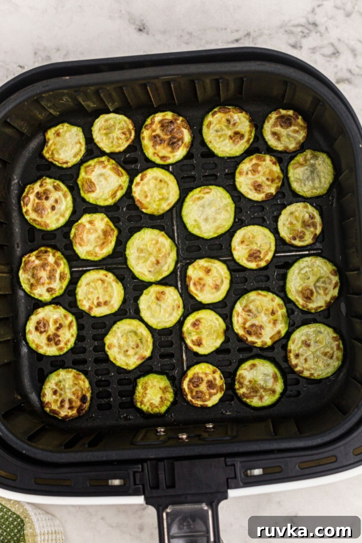 Golden Crispy Air Fryer Zucchini 6 Cooked, golden-brown air fryer zucchini slices nestled in the air fryer basket.
